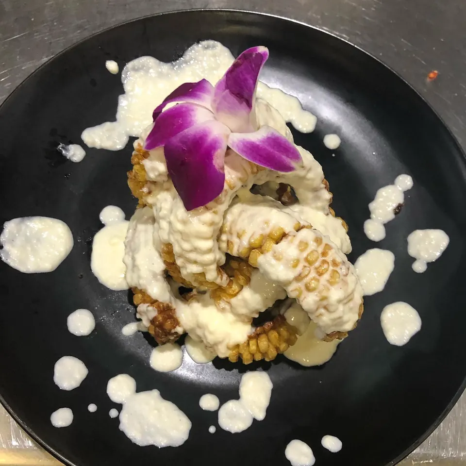 A plant-based plate with grilled corn and an orchid, by Mica